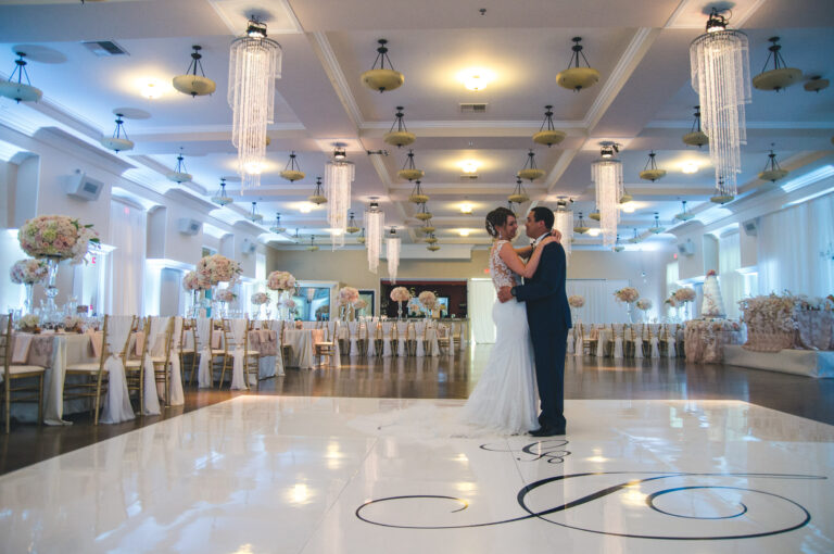 Elegant wedding venue in Bakersfield, Ca features chandeliers and tall ceilings. Venue first look as the couple takes pictures surrounded by stunning centerpieces at the guest tables.