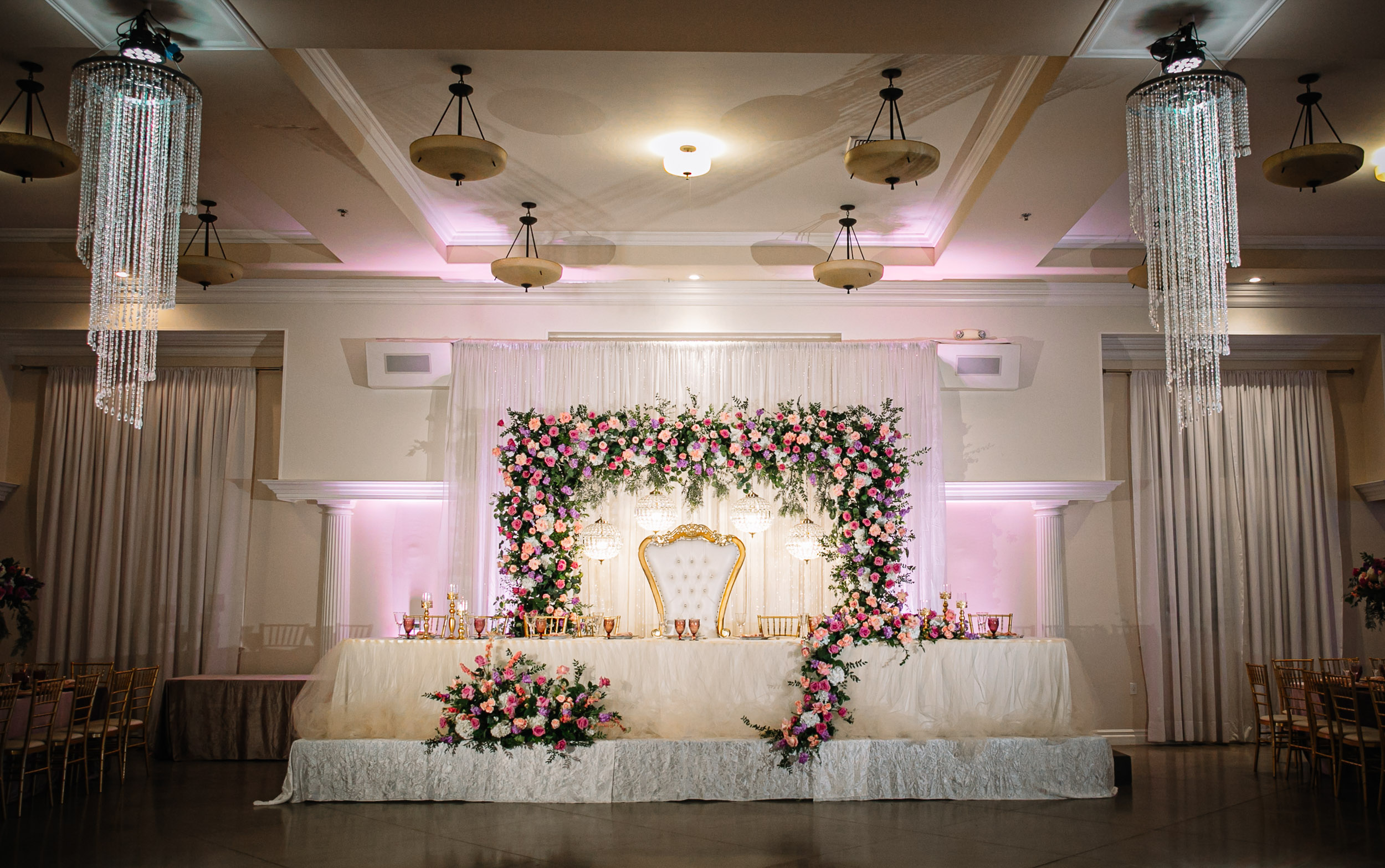 Bakersfield quince head table for an enchanted forest theme with pink and purple flowers at this quinceañera indoor venue near bakersfield.