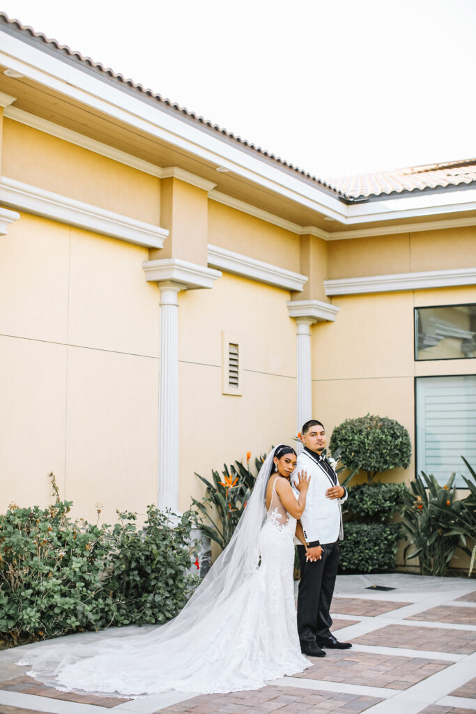 Stunning columns and architectural features of this Bakersfield wedding venue serve as the perfect backdrop for this couple's portraits. Bride has on a stunning dress with long veil.