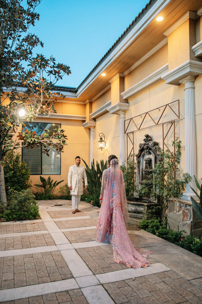 Bakersfield Indian couple taking their wedding portraits in front of the all fountain in the garden courtyard of an elegant indoor wedding reception hall.