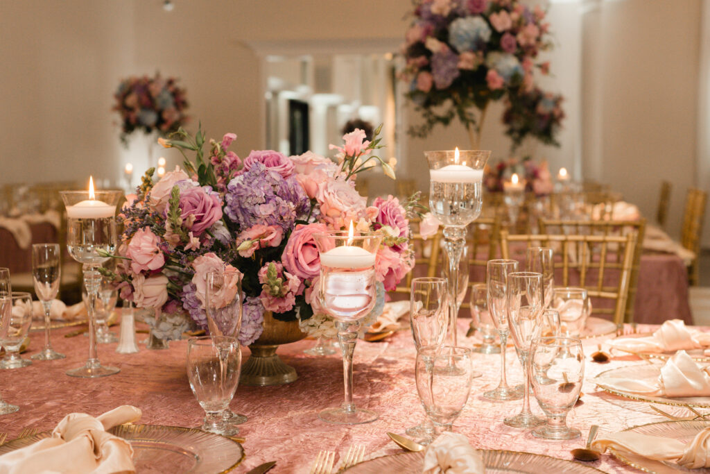 luxury quinceañera decor centerpieces in muaves, pinks, lilac, and soft blue with floating candles, glass charger plates at this bakersfield salon de fiesta