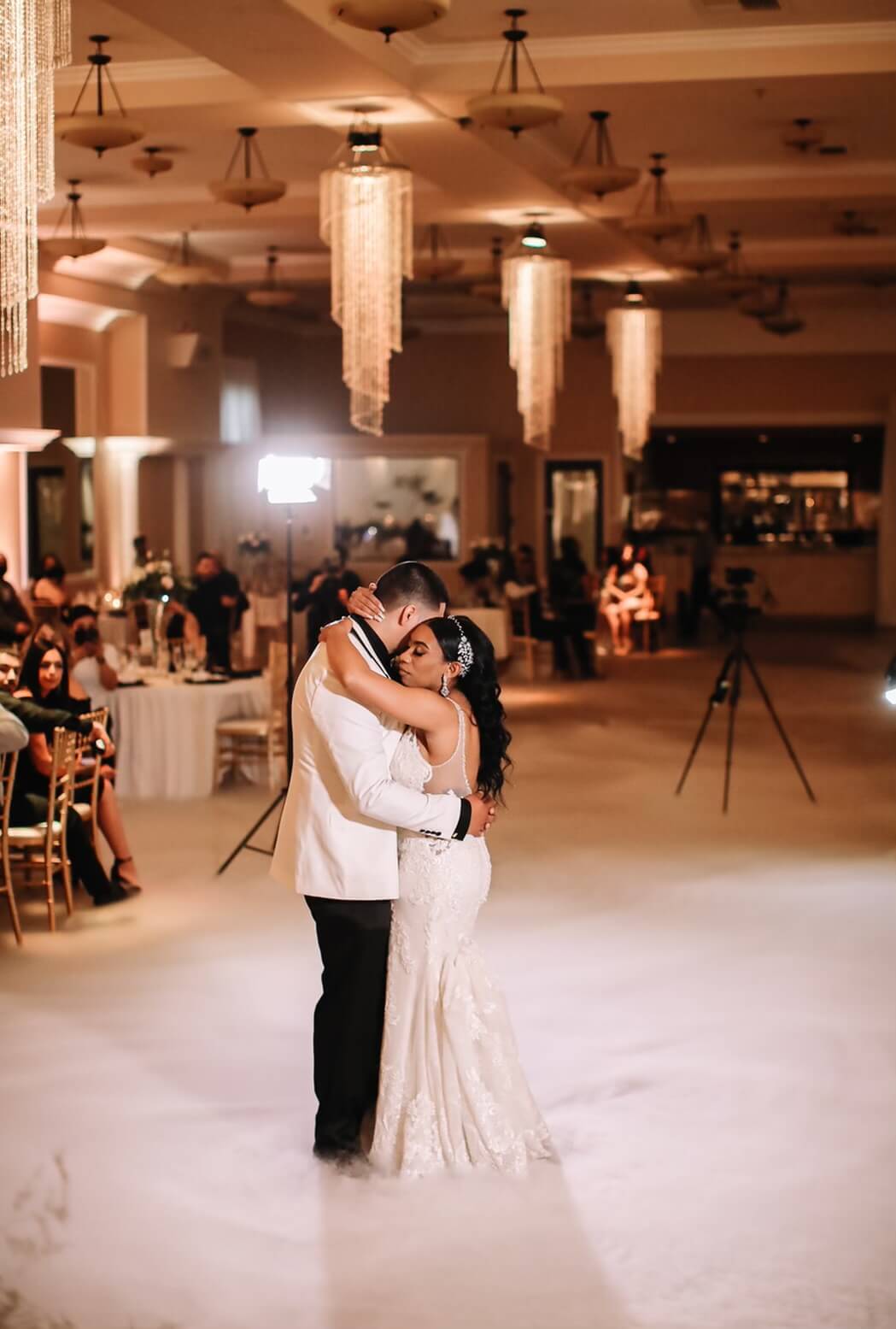 Dancing on the clouds for their first dance as husband and wife at a Bakersfield wedding venue with beautiful chandeliers.