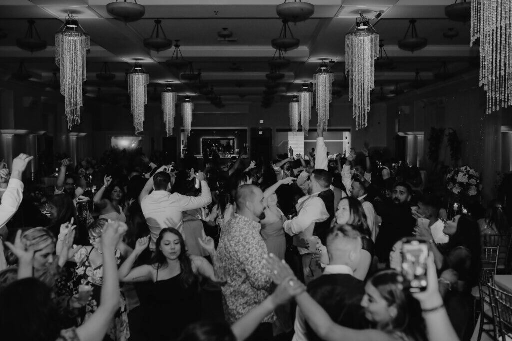 Wedding guests dance the night away at this Bakersfield reception while the venue's chandeliers shine above.