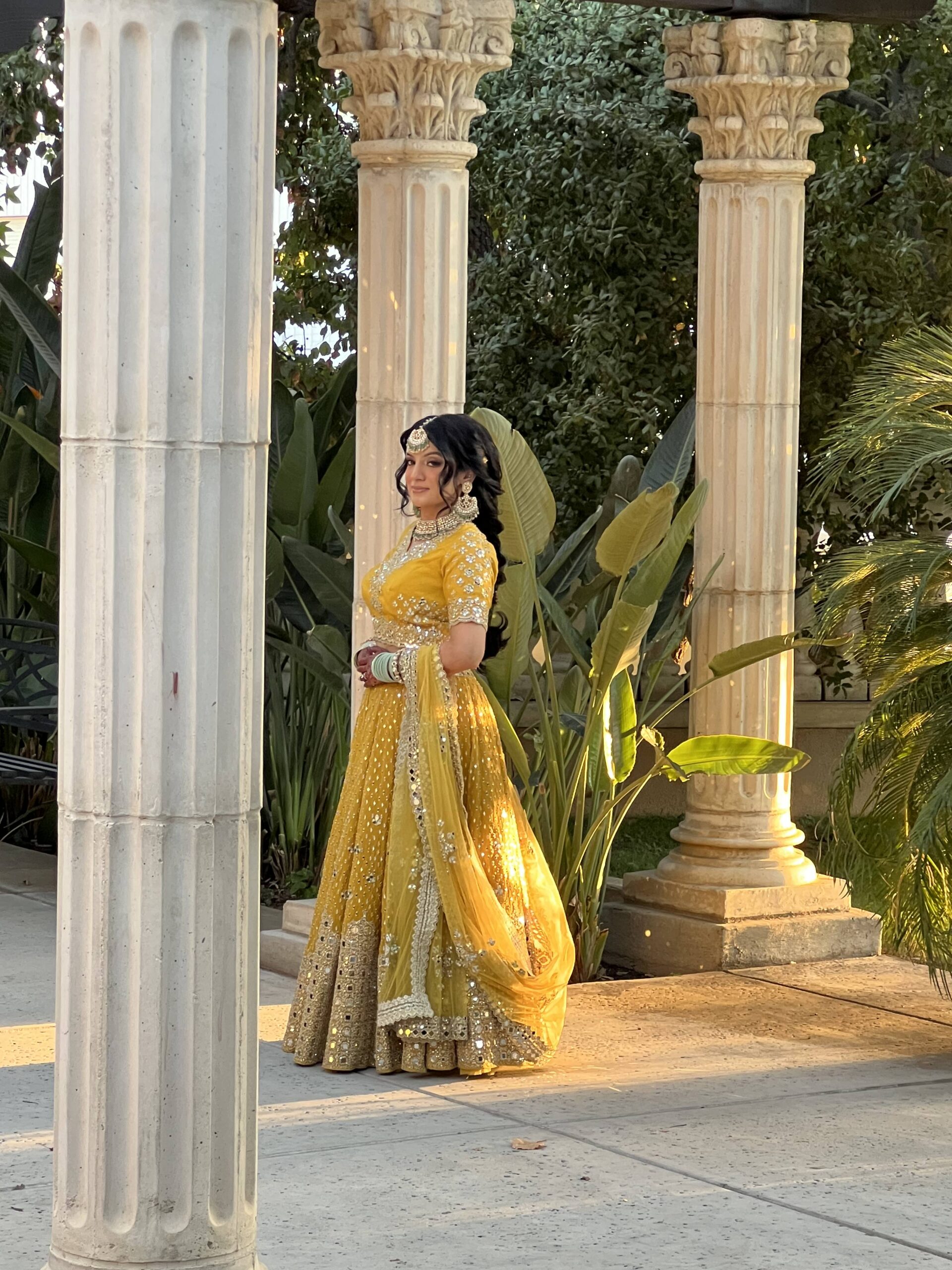 Bakersfield Indian bride in a yellow suit poses in the garden during golden hour