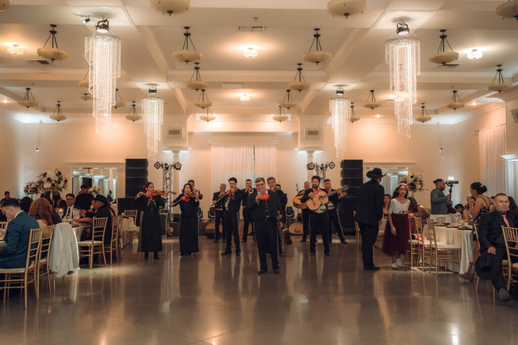 Mariachi performing for guests at this Bakersfield indoor wedding venue featuring high ceiling with stunning chandeliers.