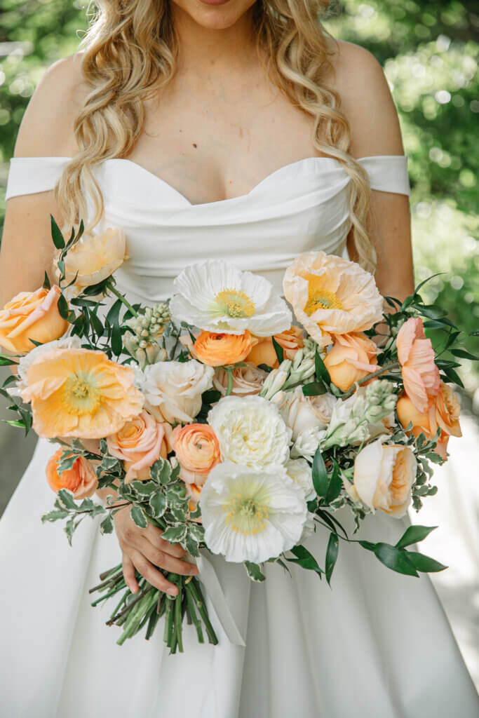Bakersfield bridal bouquet featuring double Iceland poppies, garden roses, and ranunculus in soft orange, ivory, and white for a spring styled wedding shoot.