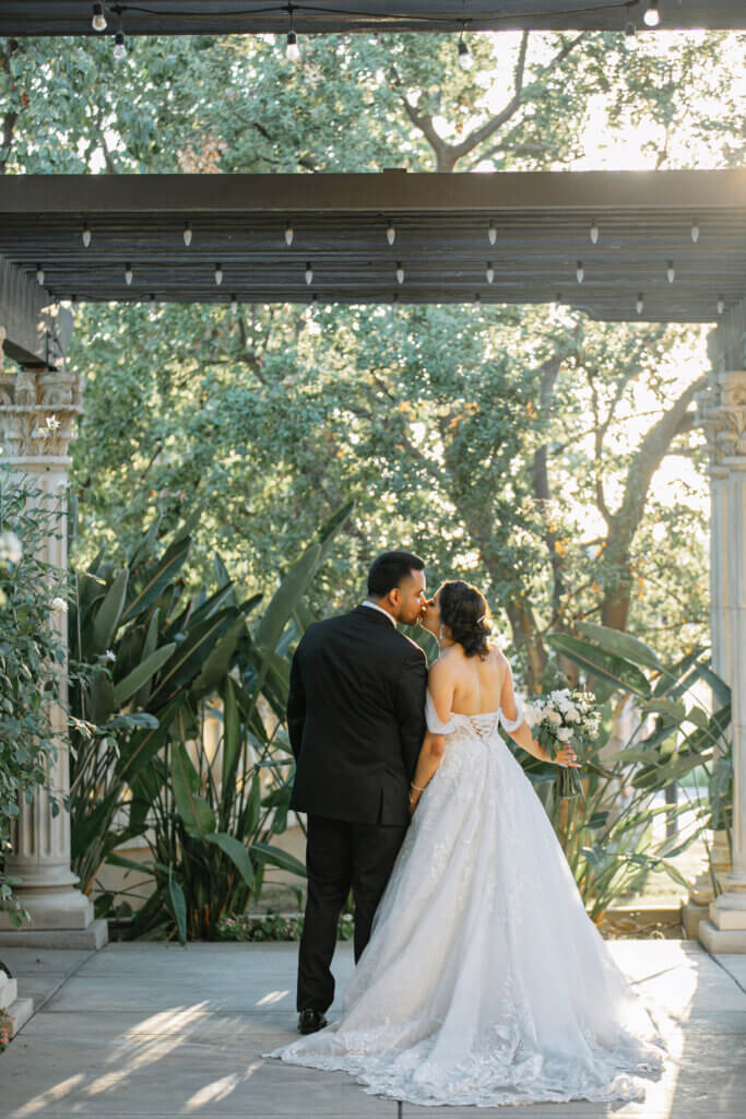 Tuscan style wedding and event venue in Bakersfield, California has a beautiful garden courtyard where this couple share a kiss.