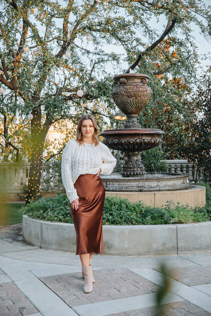 Bakersfield wedding venue manager standing in front of a fountain in the tuscan style garden courtyard