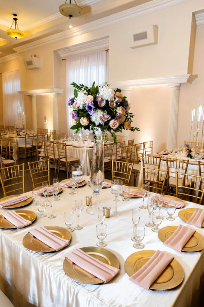indoor bakersfield reception venue for arabic and Indian weddings featuring a centerpiece in lilacs and pinks for luxury guest tables