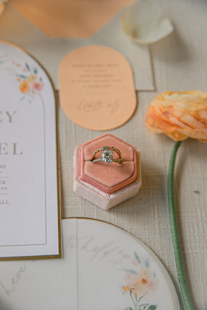 Bakersfield Spring wedding flat lay details focusing on engagement and wedding ring in a coral and blush ring box.