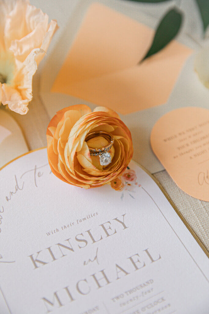 Bakersfield spring wedding flat lay with rings nestled in an orange ranunculus.
