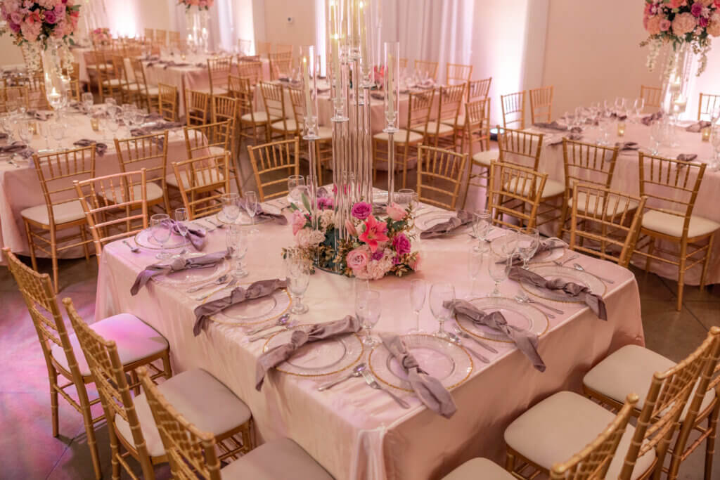 Bakersfield wedding place for quinceañeras and sweet 16s. Guest table decor featuring crystal candelabras, soft pink table linens, luxury glass charger plates, and flowers in different tones of pinks 